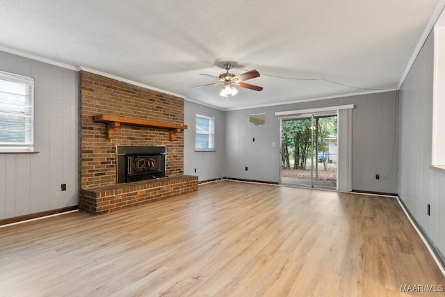 unfurnished living room with ceiling fan, a brick fireplace, light hardwood / wood-style floors, a textured ceiling, and ornamental molding