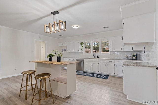 kitchen featuring sink, white cabinets, decorative backsplash, hanging light fixtures, and stainless steel dishwasher