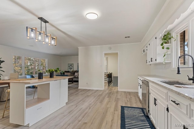 kitchen with sink, light stone counters, light wood-type flooring, stainless steel dishwasher, and white cabinets