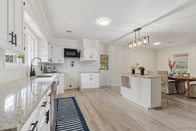 kitchen with pendant lighting, sink, white cabinets, decorative backsplash, and light hardwood / wood-style flooring