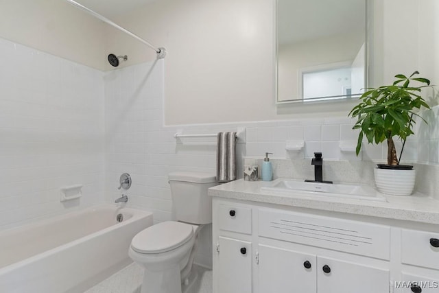 full bathroom with tile walls, vanity, toilet, and tiled shower / bath