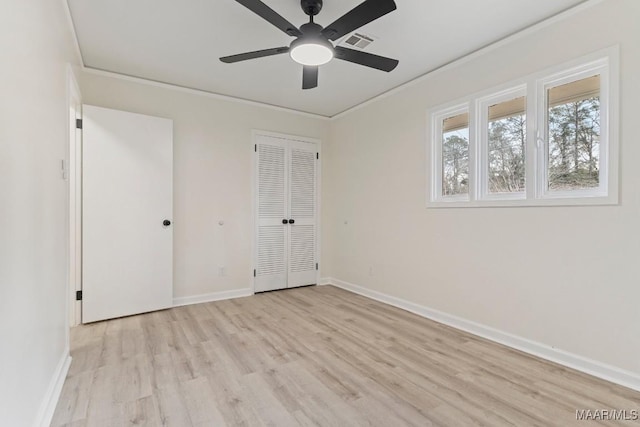 unfurnished bedroom with ornamental molding, a closet, ceiling fan, and light wood-type flooring