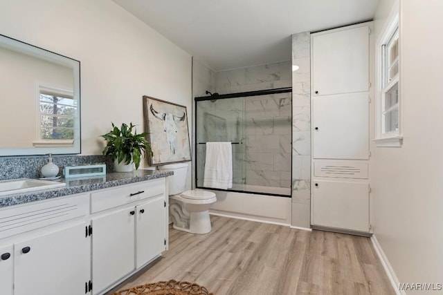 full bathroom featuring vanity, wood-type flooring, toilet, and combined bath / shower with glass door