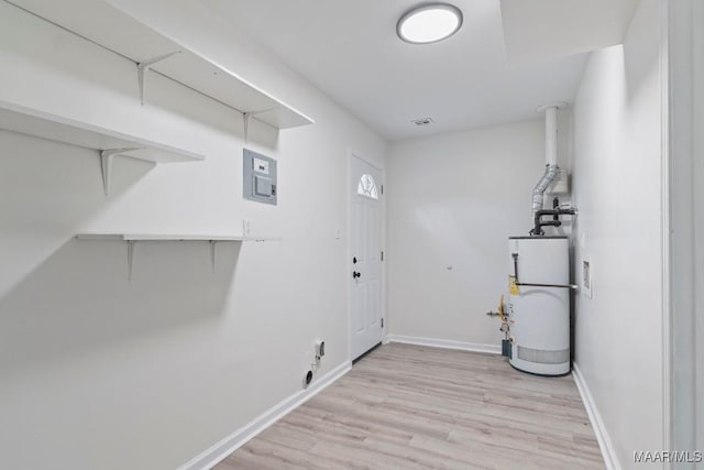 clothes washing area featuring gas water heater and light hardwood / wood-style flooring