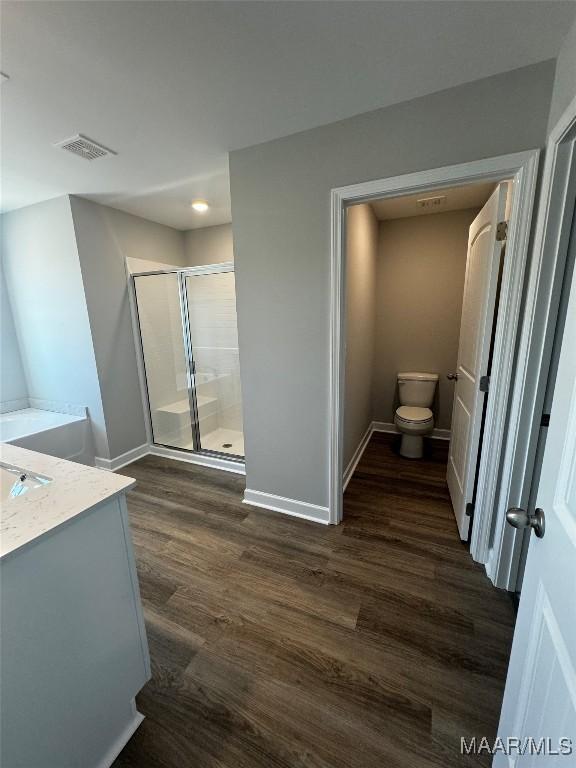 bathroom featuring vanity, hardwood / wood-style flooring, a shower with shower door, and toilet