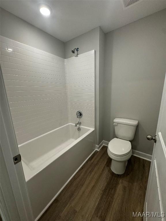 bathroom featuring hardwood / wood-style flooring, tiled shower / bath, and toilet