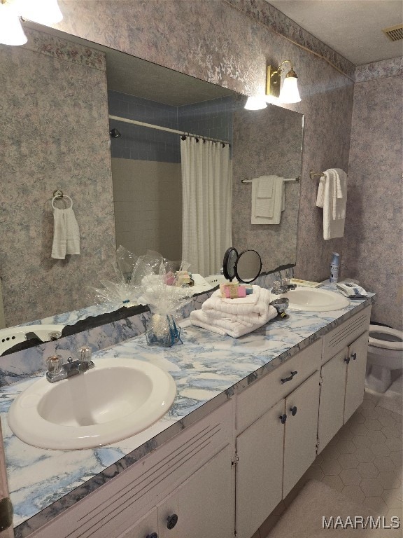 bathroom with curtained shower, vanity, tile patterned floors, and toilet