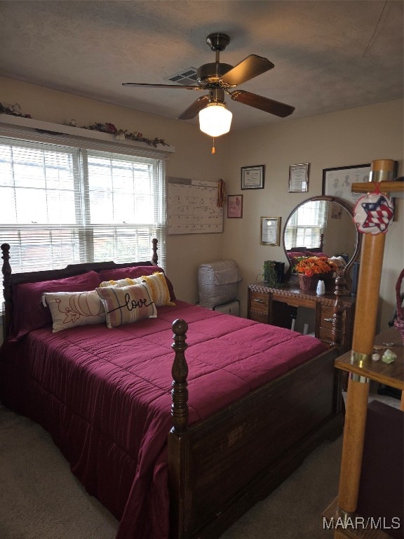 bedroom with ceiling fan, a textured ceiling, and carpet floors