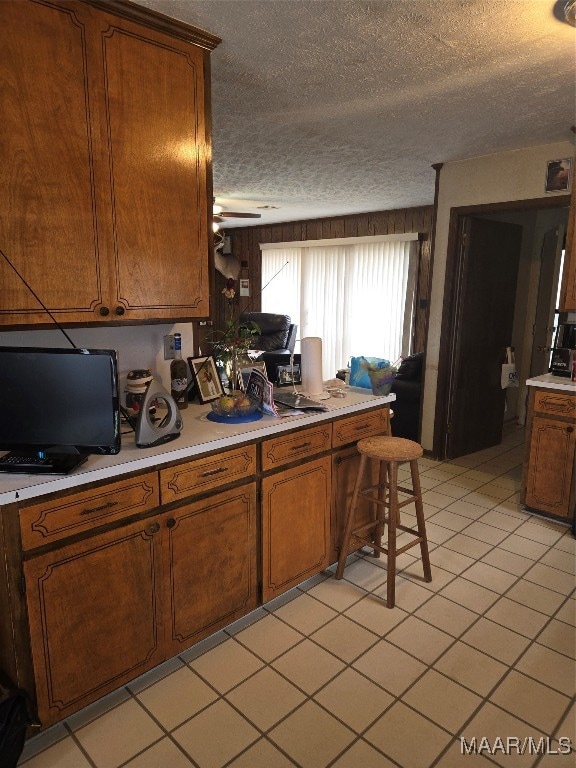 kitchen with light tile patterned flooring, ceiling fan, a textured ceiling, and a breakfast bar