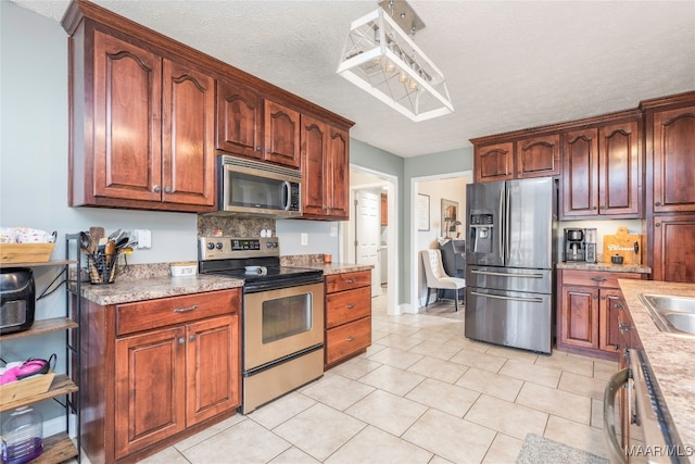 kitchen featuring stainless steel appliances, a textured ceiling, light tile patterned floors, and sink