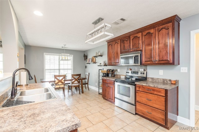 kitchen featuring sink, appliances with stainless steel finishes, a textured ceiling, light tile patterned floors, and hanging light fixtures