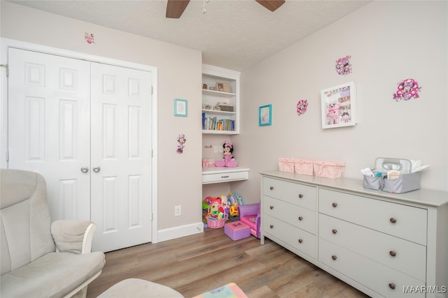 playroom featuring light wood-type flooring, a textured ceiling, and ceiling fan