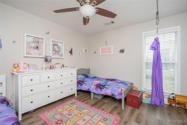 bedroom featuring ceiling fan, wood-type flooring, and a textured ceiling