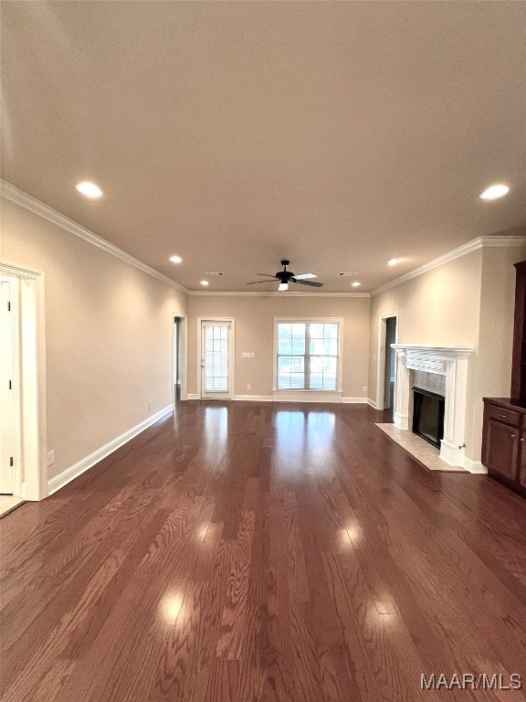 unfurnished living room with hardwood / wood-style floors, ceiling fan, a fireplace, and crown molding