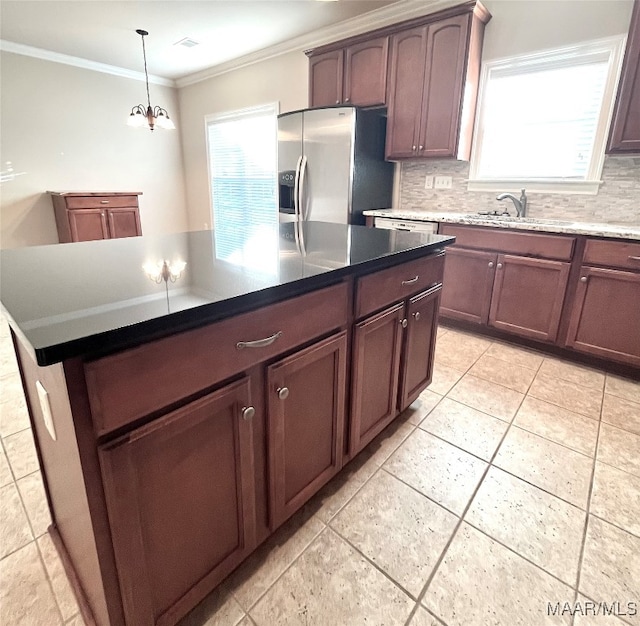 kitchen with a center island, sink, tasteful backsplash, ornamental molding, and stainless steel fridge