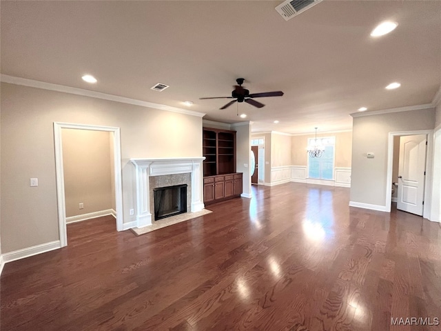 unfurnished living room featuring ceiling fan with notable chandelier, a tiled fireplace, crown molding, and dark hardwood / wood-style flooring