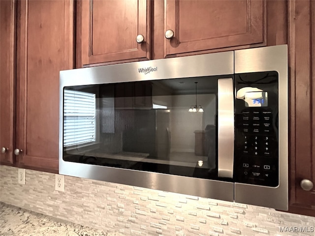 details with light stone countertops and decorative light fixtures