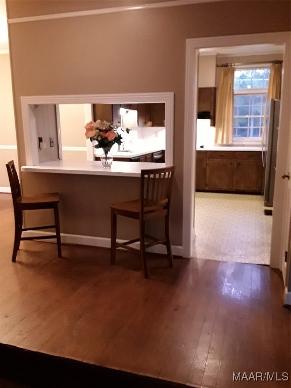 interior space featuring kitchen peninsula, a kitchen breakfast bar, stainless steel refrigerator, and wood-type flooring