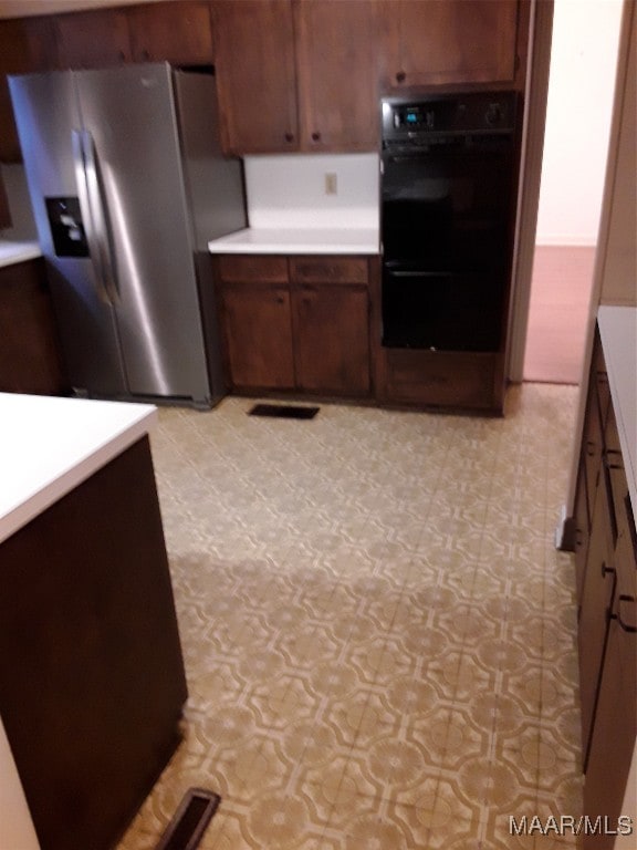 kitchen featuring double oven, dark brown cabinets, and stainless steel refrigerator with ice dispenser