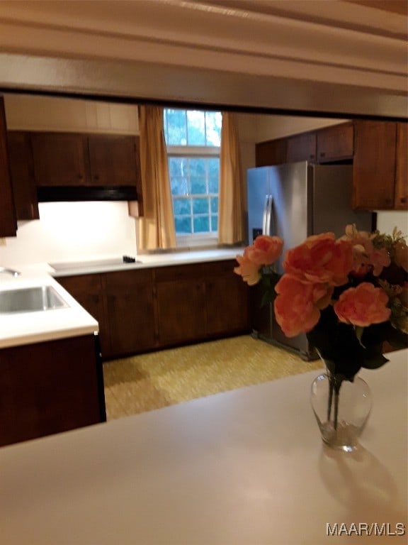 kitchen featuring dark brown cabinetry, sink, and stainless steel refrigerator