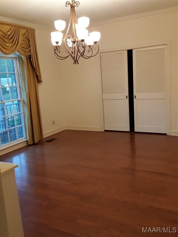 spare room with ornamental molding, dark wood-type flooring, and a chandelier