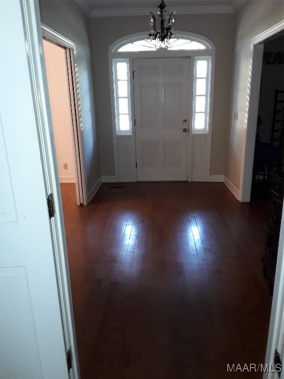 entryway featuring dark hardwood / wood-style floors, an inviting chandelier, and crown molding