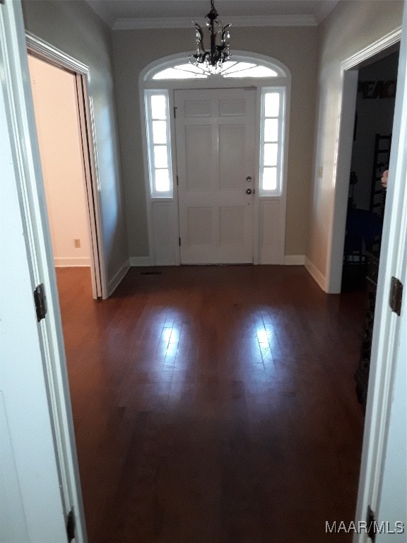 entryway featuring crown molding, dark hardwood / wood-style floors, and an inviting chandelier