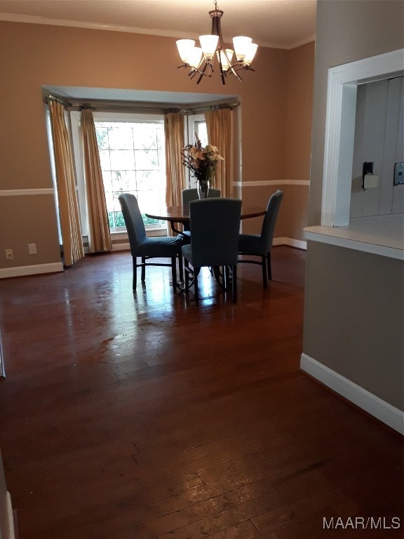 dining space featuring dark hardwood / wood-style flooring, crown molding, and a notable chandelier