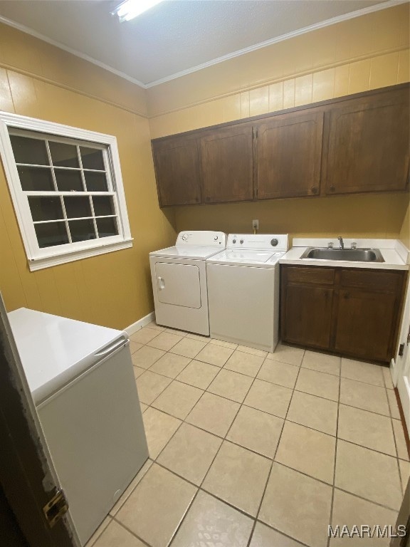 laundry room with cabinets, sink, ornamental molding, light tile patterned flooring, and washing machine and clothes dryer