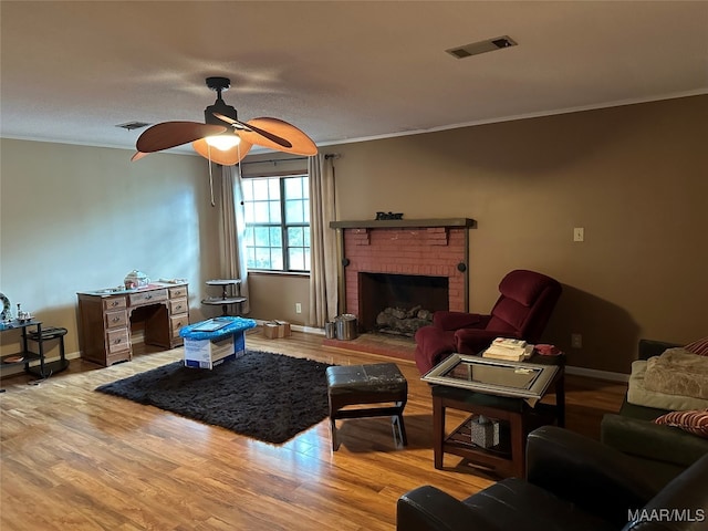 living room with hardwood / wood-style floors, a fireplace, ceiling fan, and crown molding