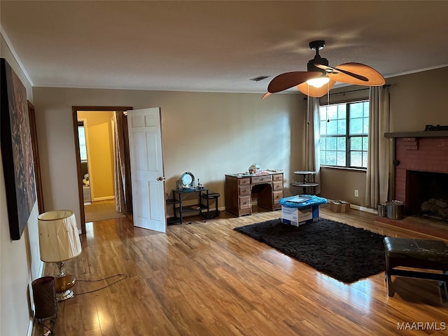 living room featuring ceiling fan, crown molding, hardwood / wood-style floors, a textured ceiling, and a fireplace