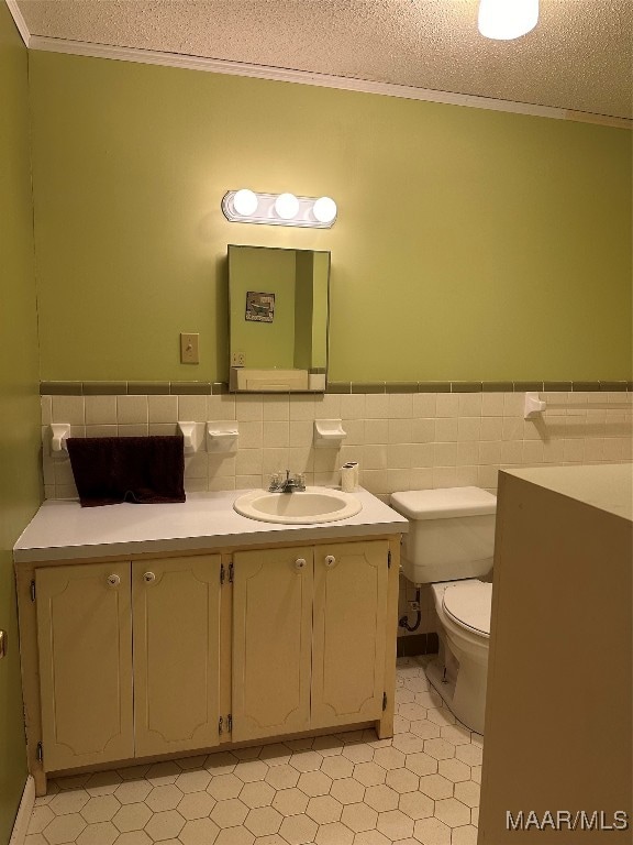 bathroom with tile patterned flooring, crown molding, a textured ceiling, toilet, and vanity