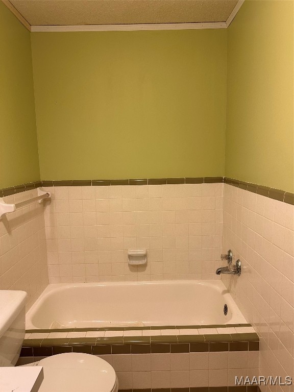 bathroom with a textured ceiling, toilet, and a tub to relax in