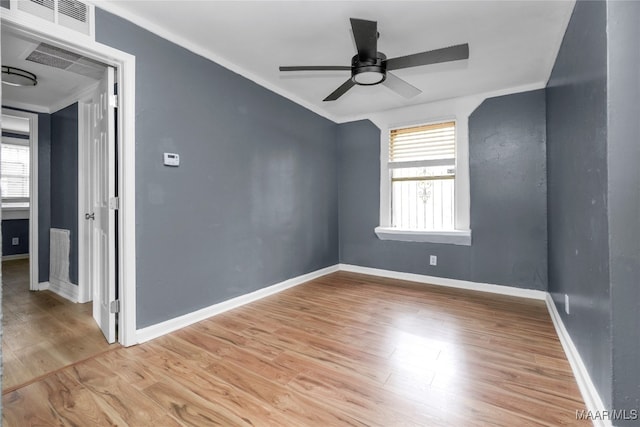 empty room featuring light wood-type flooring, plenty of natural light, ceiling fan, and crown molding