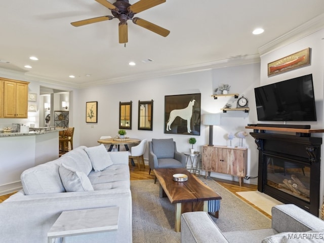 living room featuring ornamental molding, ceiling fan, and light hardwood / wood-style flooring