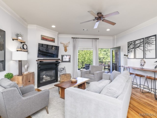 living room with ceiling fan, light wood-type flooring, and ornamental molding