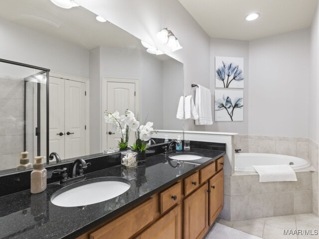 bathroom with vanity, tile patterned flooring, and a relaxing tiled tub