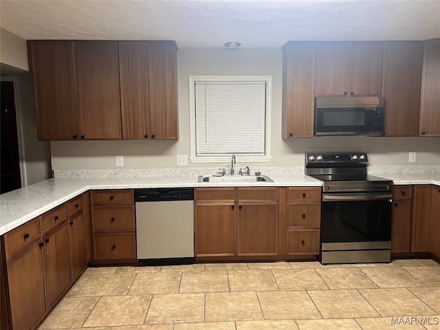 kitchen with appliances with stainless steel finishes, sink, and a textured ceiling