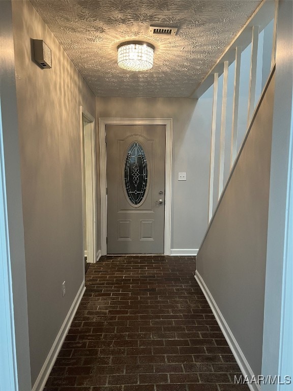 doorway to outside featuring a textured ceiling