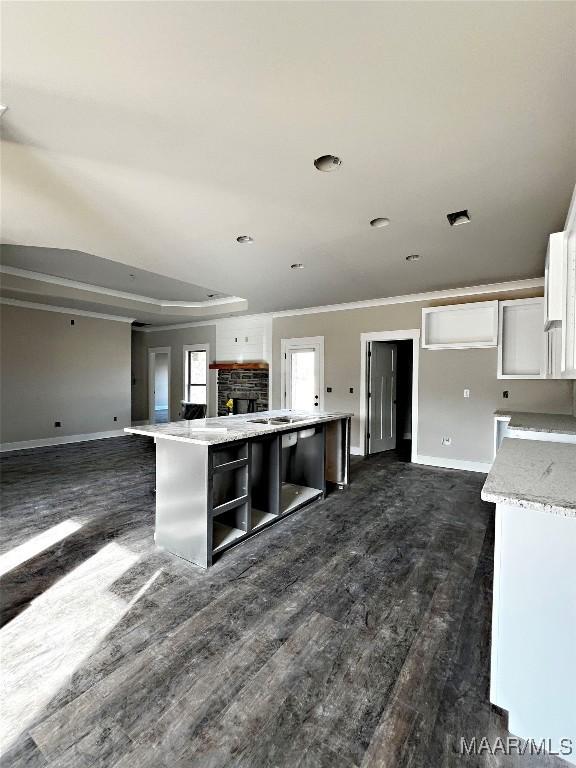 kitchen with crown molding, light stone counters, dark hardwood / wood-style floors, a kitchen island, and white cabinets