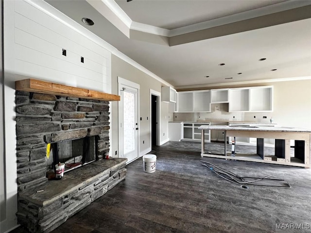 living room with ornamental molding, dark hardwood / wood-style floors, and a stone fireplace