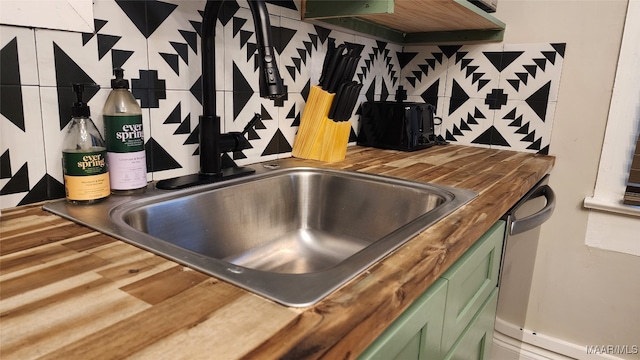 details with wooden counters, stainless steel dishwasher, tasteful backsplash, and green cabinets