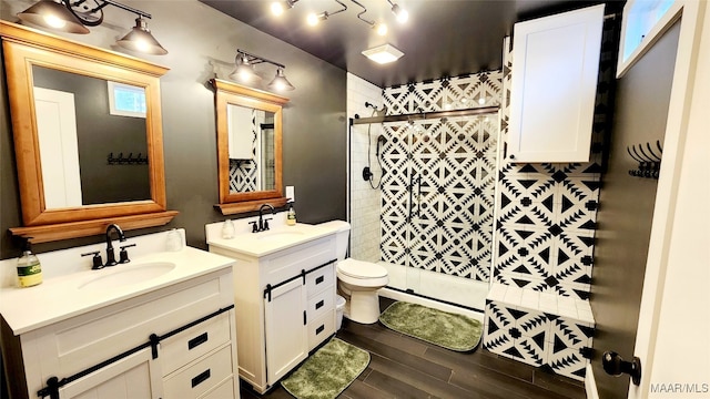 bathroom featuring toilet, vanity, wood-type flooring, and a shower with door