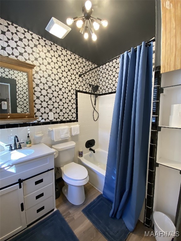 full bathroom featuring wood-type flooring, shower / bath combo with shower curtain, toilet, tile walls, and vanity