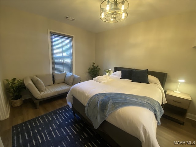 bedroom featuring an inviting chandelier and dark hardwood / wood-style flooring