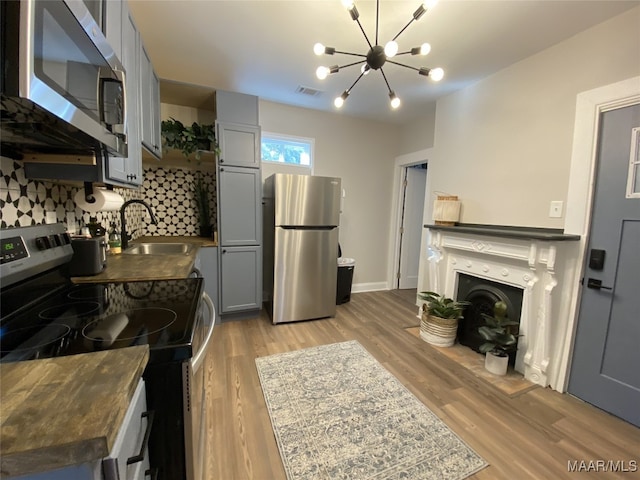 kitchen featuring backsplash, appliances with stainless steel finishes, gray cabinets, sink, and light hardwood / wood-style floors