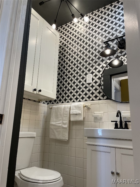 bathroom featuring toilet and tile walls