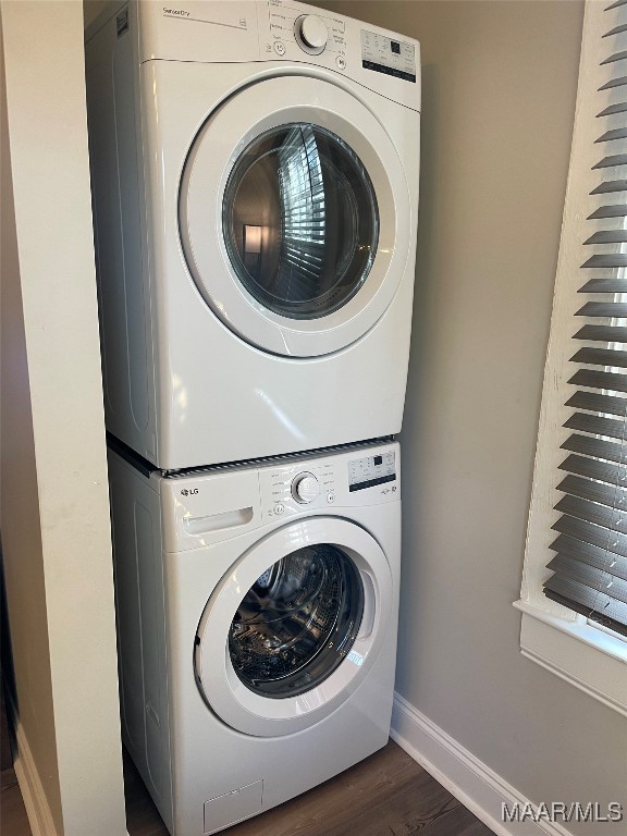 laundry area featuring stacked washer and dryer and dark hardwood / wood-style floors