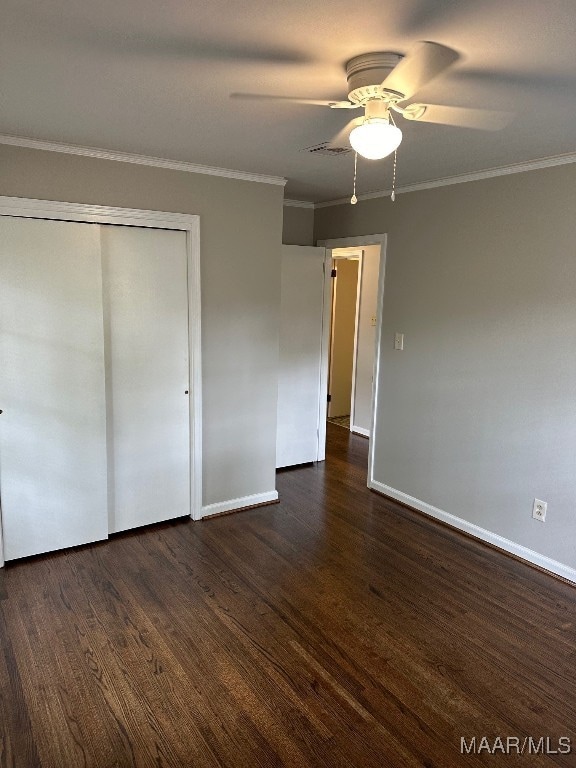 unfurnished bedroom with dark wood-type flooring, a closet, ceiling fan, and crown molding