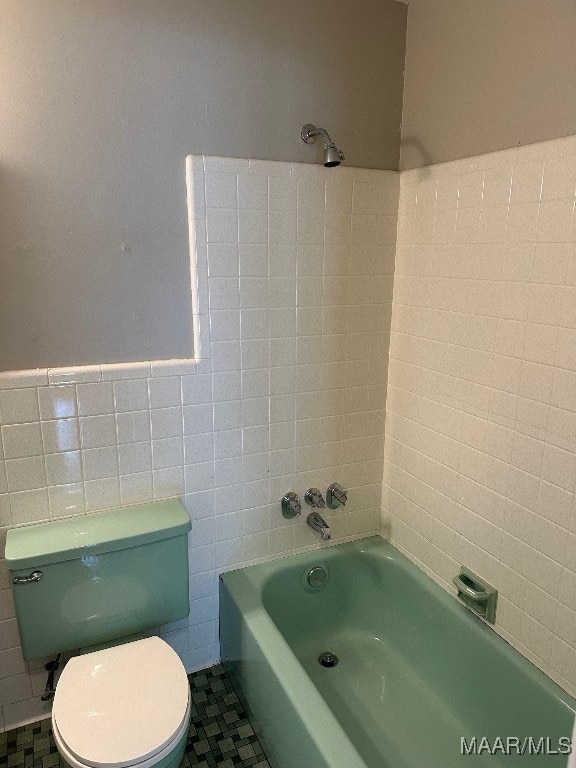 bathroom with tile patterned floors, toilet, a bathtub, and tile walls